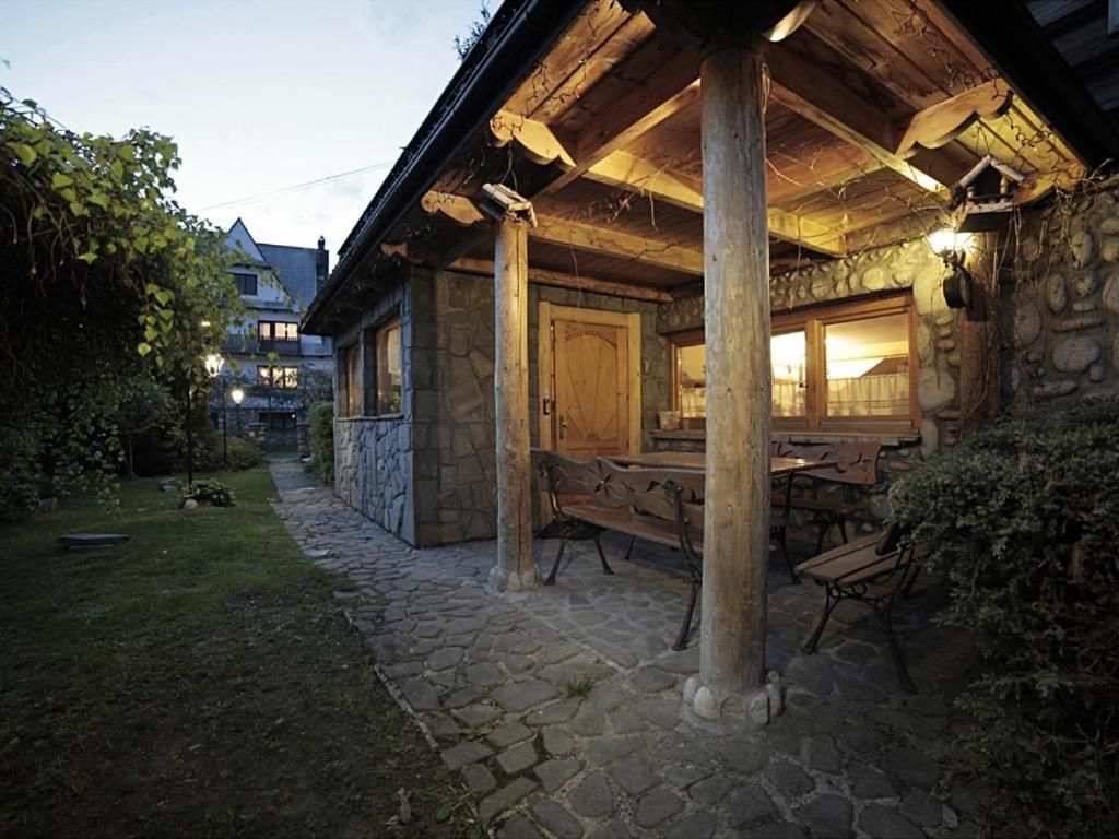 um edifício de pedra com uma pérgola de madeira e um banco em Pod Strzechą em Białka Tatrzanska