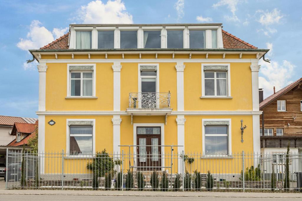 uma casa amarela com uma cerca em frente em Apartment Tuna em Sigmarszell