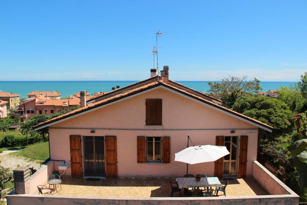 una piccola casa bianca con un ombrello e un tavolo di Appartamenti Pura Vida a Fano