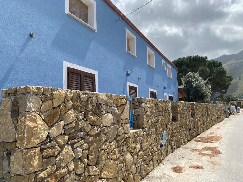 a blue building next to a stone wall at B&B Pelagos in Castellammare del Golfo
