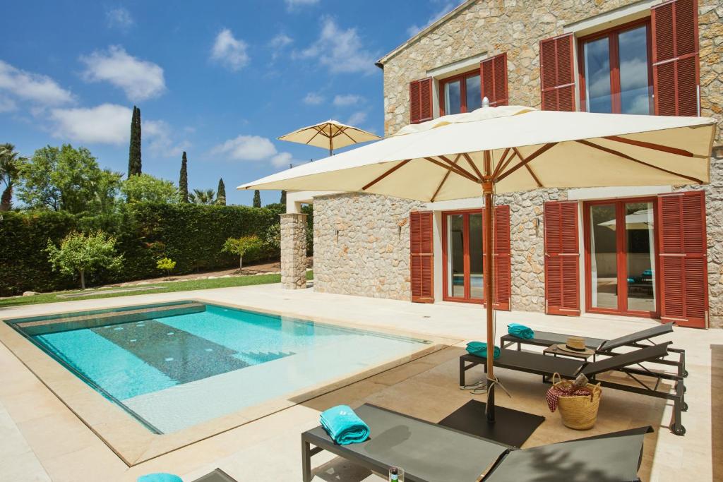 uma villa com uma piscina e um guarda-sol em Villa Jade by Cap Vermell Estate em Canyamel