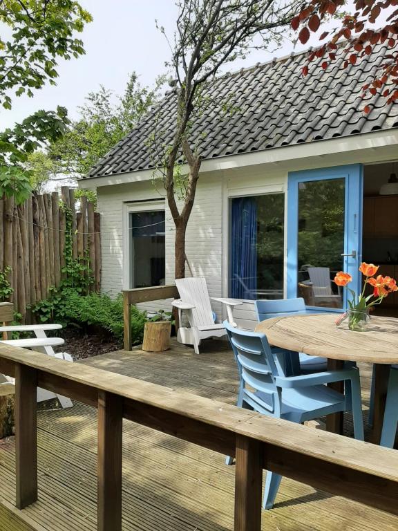 eine Holzterrasse mit einem Tisch und Stühlen darauf in der Unterkunft Boshuisje Petten aan Zee in Petten