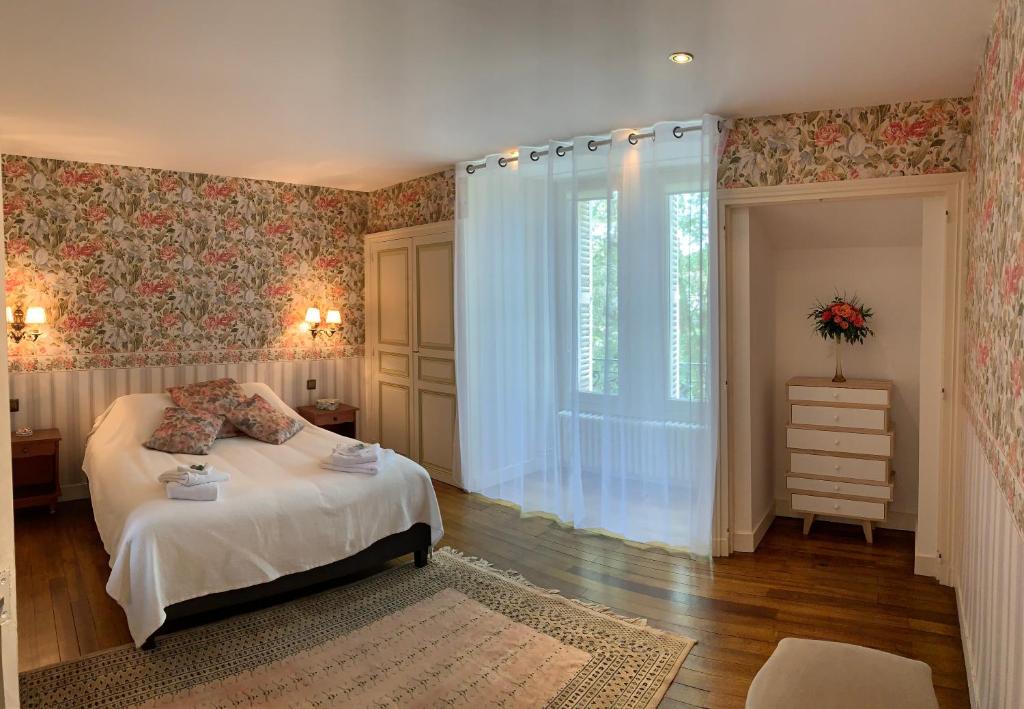 a bedroom with a bed and a large window at Château l&#39;Hubertière, classé du tourisme 4 étoiles in Bouresse