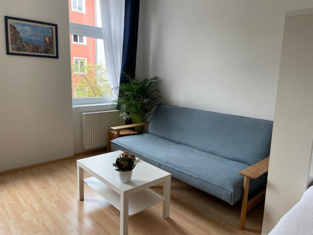 ein Wohnzimmer mit einem blauen Sofa und einem Tisch in der Unterkunft Central Sunny Flat with Free Parking in Wien