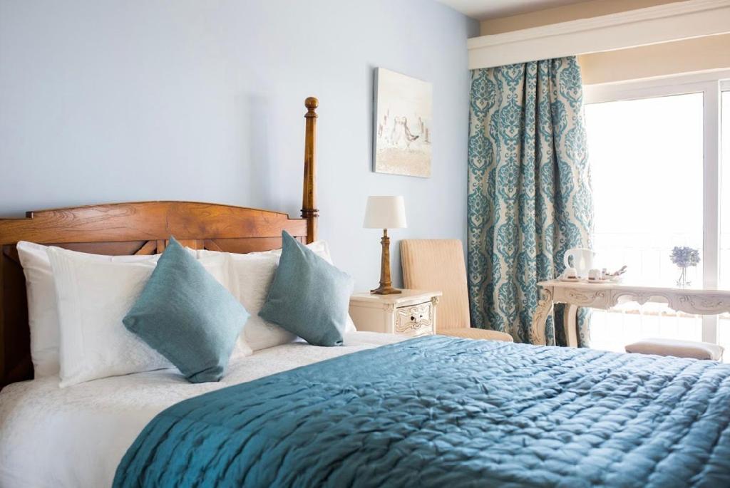 Haven Rooms Sea View at The Blue Haven في دونيجال: غرفة نوم بسرير وبطانية زرقاء ونافذة