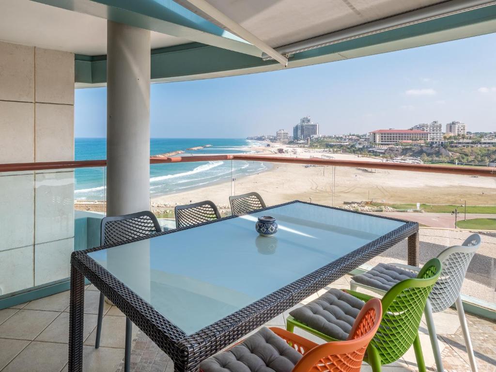 een glazen tafel en stoelen op een balkon met uitzicht op het strand bij Front of Beach next Ritz Hotel - 3 Bedroom& 3 Bathroom in Herzelia 