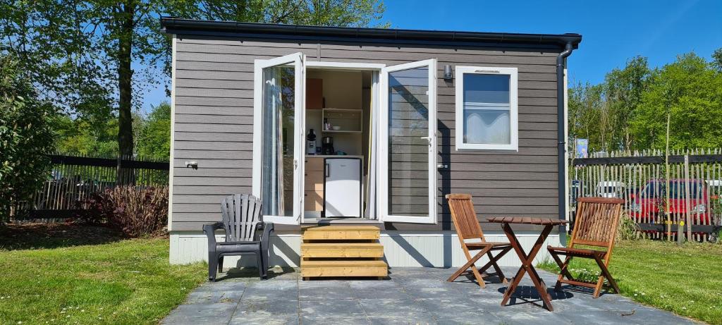 Mini-chalet - Vakantiepark 't Urkerbos في أورك: منزل صغير صغير مع كراسي وطاولة