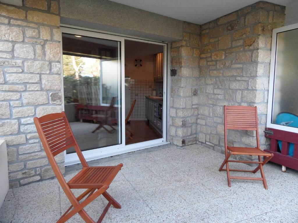 two wooden chairs sitting on a patio with a window at REF 005 Studio pour deux personnes avec terrasse résidence avec piscine PORT CROUESTY ARZON in Arzon