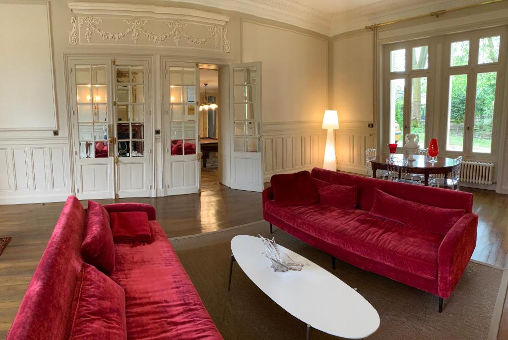 a living room with a red couch and a surfboard at Château l&#39;Hubertière, classé du tourisme 4 étoiles in Bouresse