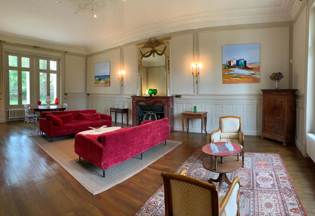 a living room with a red couch and a fireplace at Château l&#39;Hubertière, classé du tourisme 4 étoiles in Bouresse