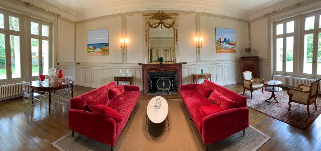 a living room with two red couches and a fireplace at Château l&#39;Hubertière, classé du tourisme 4 étoiles in Bouresse