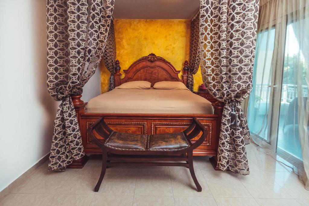 a bedroom with a wooden bed with curtains and a chair at Villa Mika Near Ialysos Beach in Ialysos