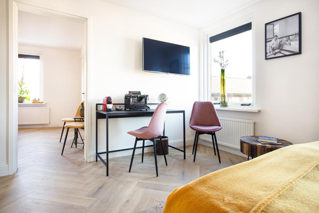 a bedroom with a desk and two pink chairs at Hotel Snouck van Loosen in Enkhuizen