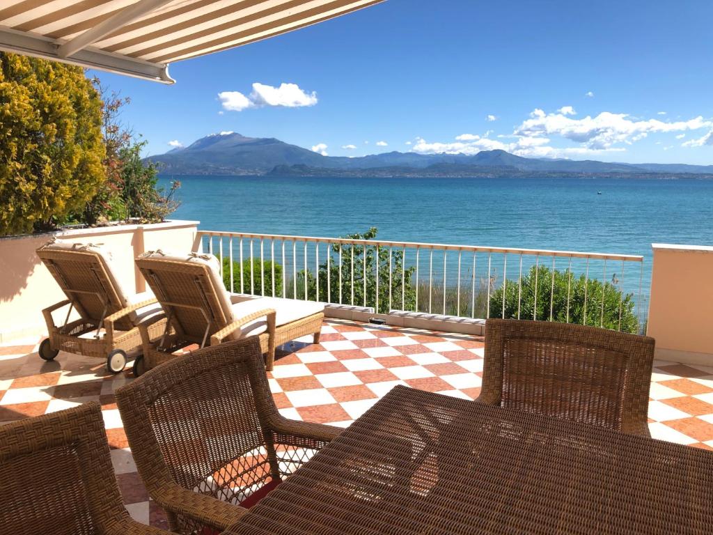 d'une terrasse avec des chaises et une vue sur l'eau. dans l'établissement Lake Front Luxury Suites, à Sirmione