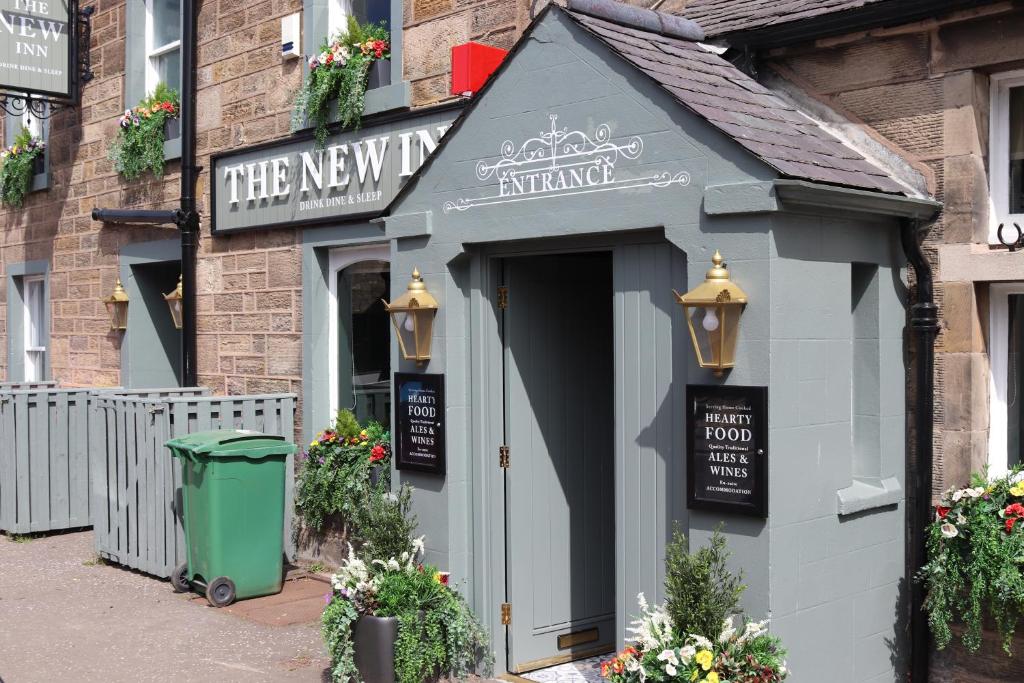 a small shop with a green trash can in front of it at The New Inn in Fife