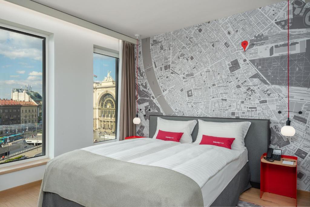 a bedroom with a large bed with red pillows at IntercityHotel Budapest in Budapest