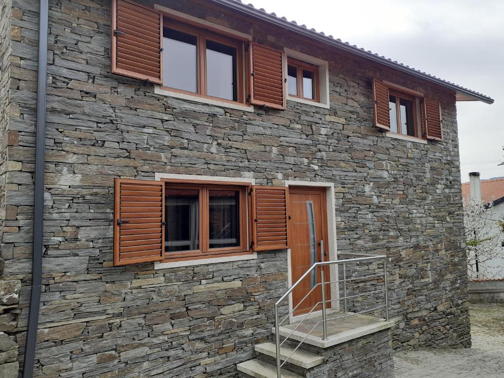 Casa de piedra con ventanas de madera y escalera en Casa Mota Pinto en Castro Daire