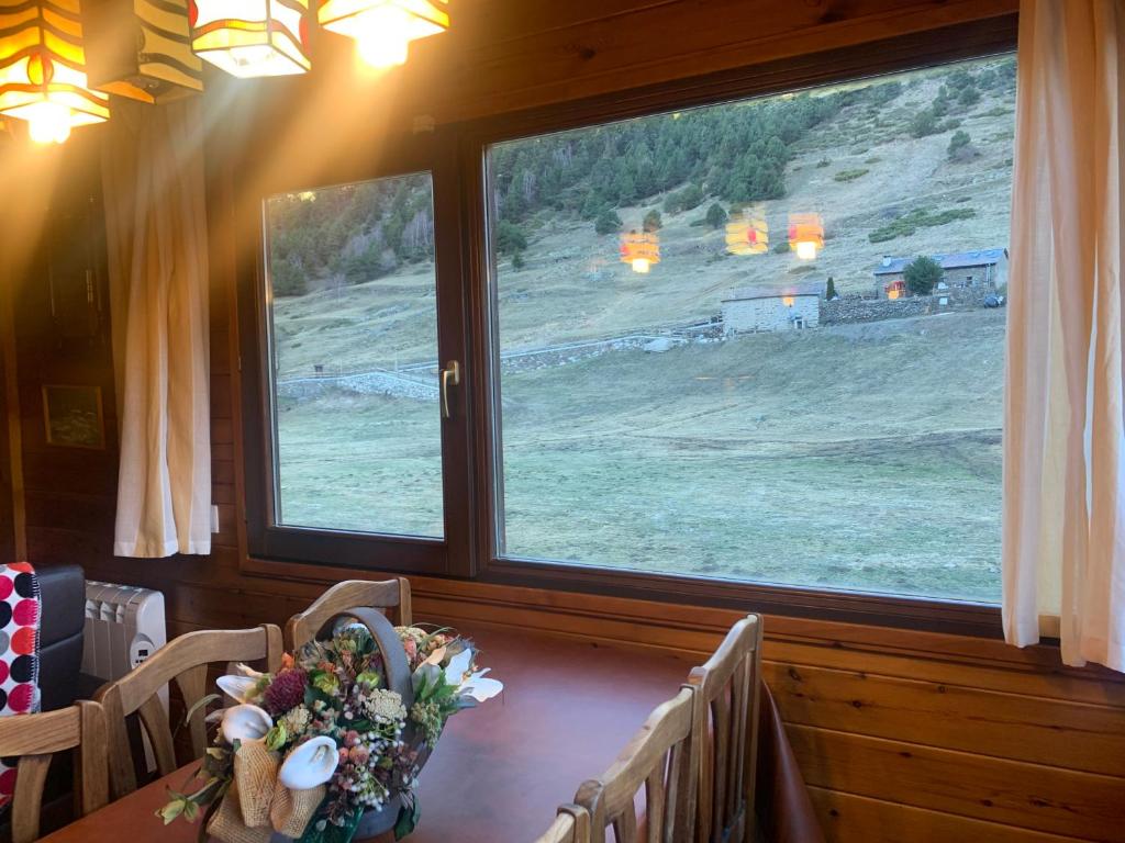 einen Tisch mit einer Blumenvase vor einem Fenster in der Unterkunft PANORAMIC - Peu del Riu 502 - Vall d'Incles - Soldeu in Incles