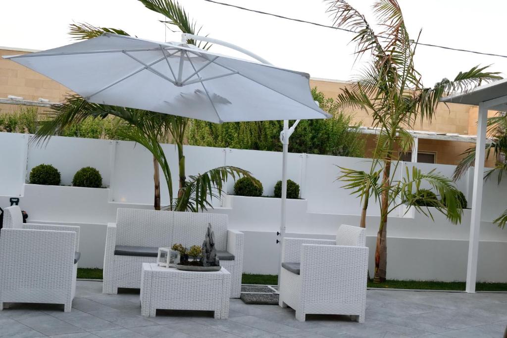 a white patio with white chairs and an umbrella at Arneo Terra del Sole in Torre Lapillo