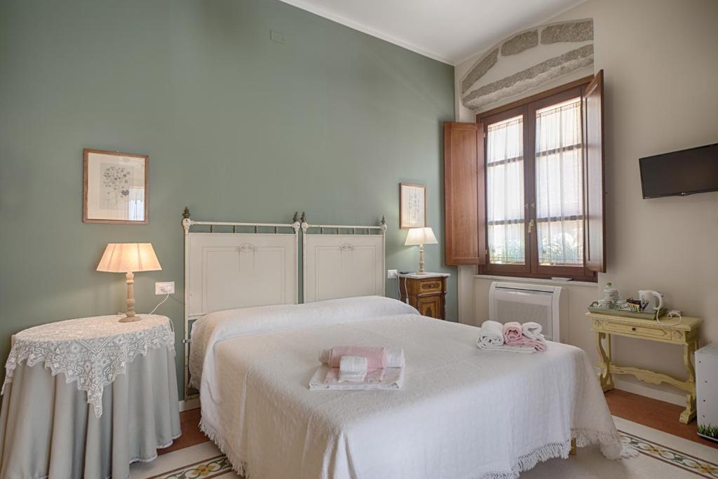 a white bedroom with two beds and a window at B&B A casa di Teresa in Olbia