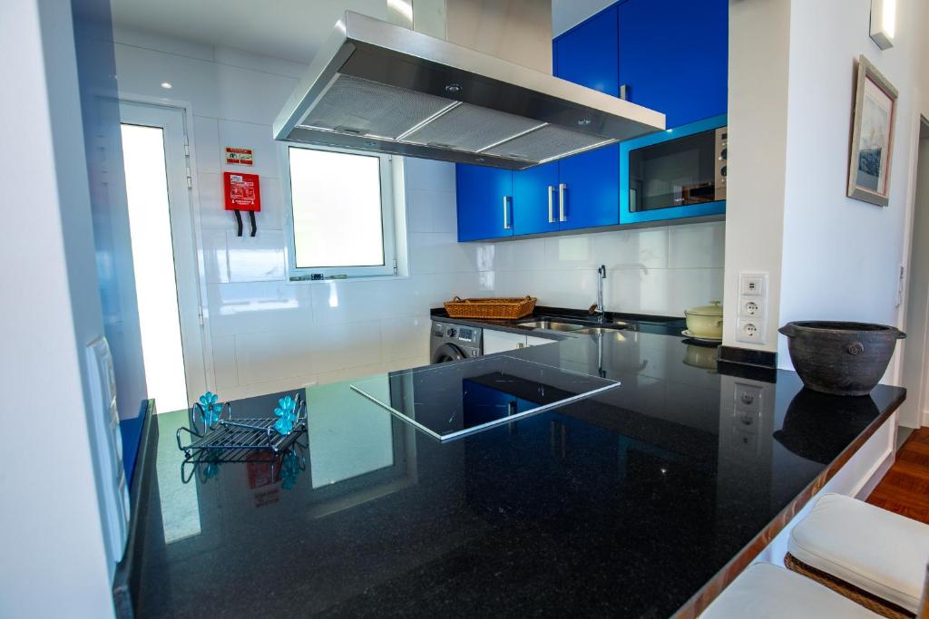 una cucina con armadi blu e ripiano in vetro di Casa Maravilha III a Caniço