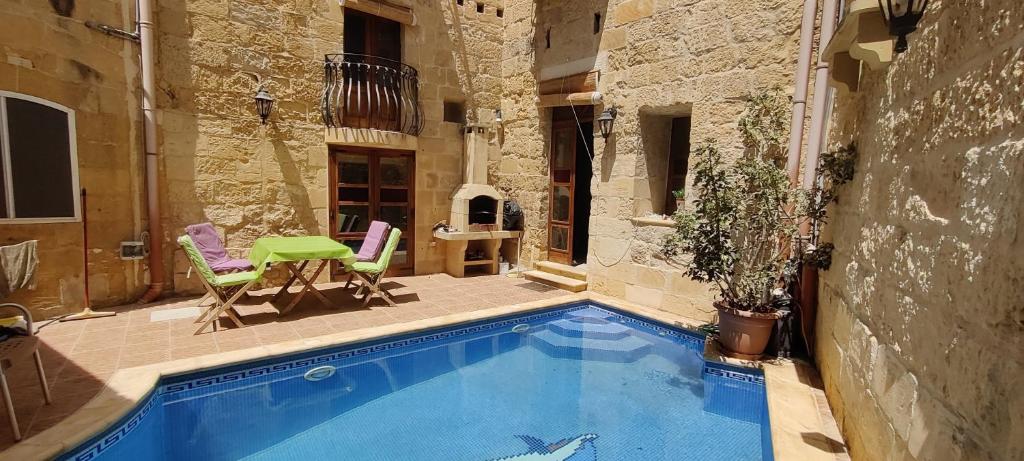 a swimming pool with two chairs and a table at Manuel's Farmhouse in Kerċem