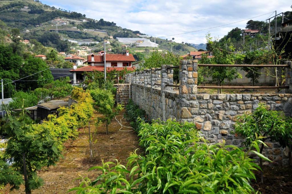 un jardin avec un mur en pierre et des plantes dans l'établissement Le Rose, à San Biagio della Cima