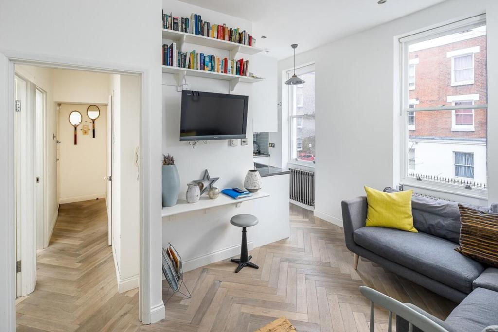 a living room with a couch and a tv on a wall at Amazing Cosy Central London Apartment 3 mins to Marylebone in London