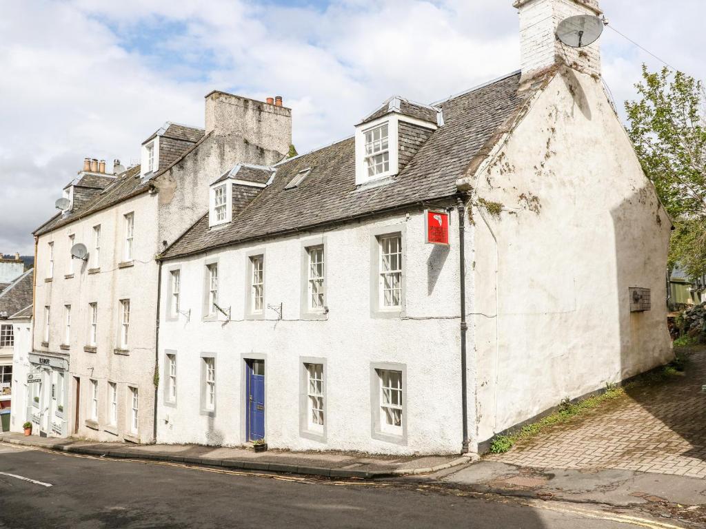 un viejo edificio blanco al lado de una calle en Springwells en Dunkeld