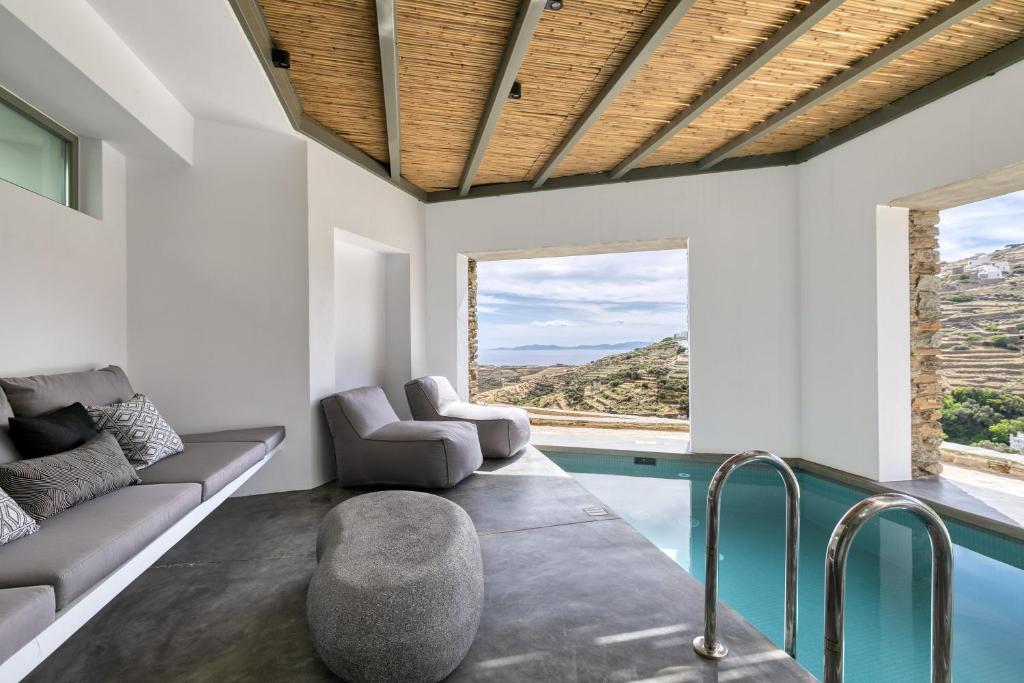 a living room with a swimming pool and a couch at Tinos Dove Suites in Triandáros