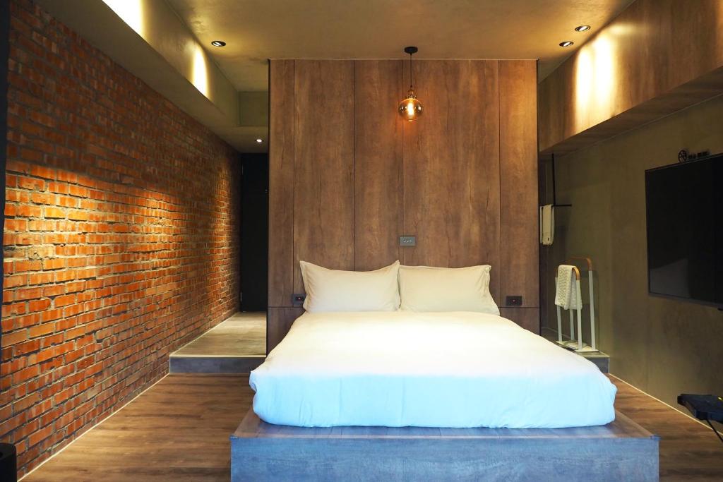 a bedroom with a white bed and a brick wall at PInHOuse in Kaohsiung