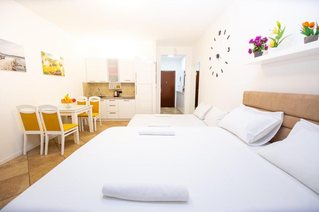 um quarto branco com 2 camas e uma mesa em Apartment Studio Premier em Rafailovici