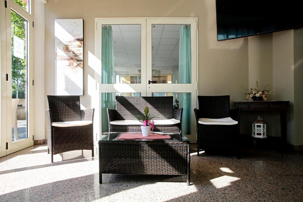 un porche con sillas y una mesa con una planta en Hotel Serafini, en Misano Adriatico