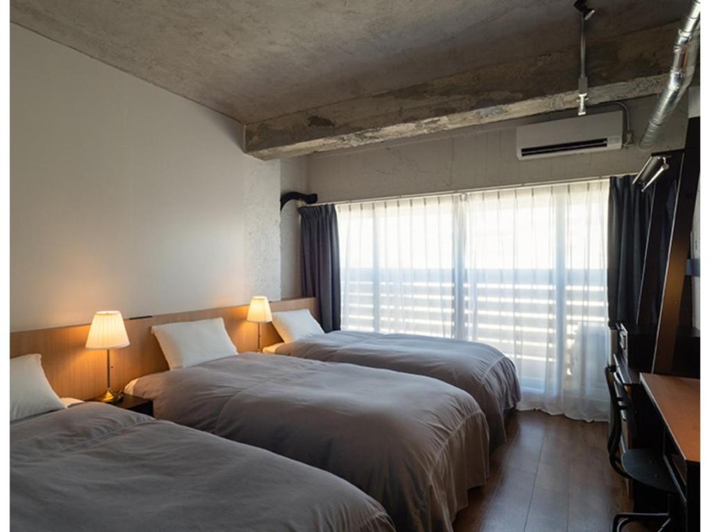 two beds in a room with a window at SHIRAHAMA KEY TERRACE SEAMORE RESIDENCE - Vacation STAY 35165v in Kanayama