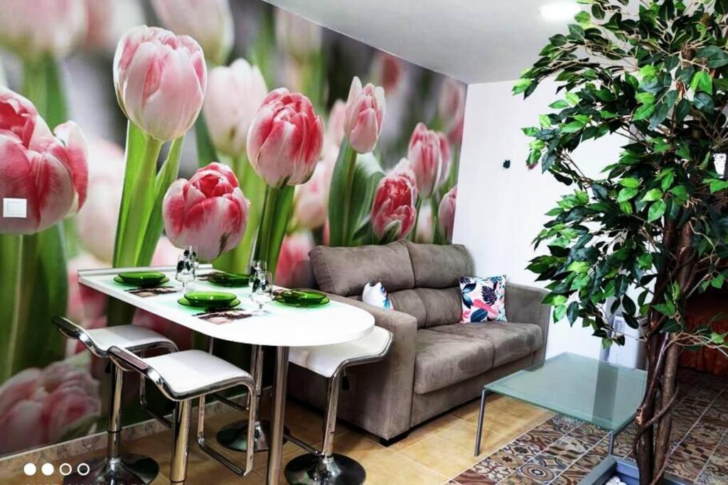 een kamer met een tafel, een bank en bloemen bij Apartamento Los Tulipanes in Lumpiaque