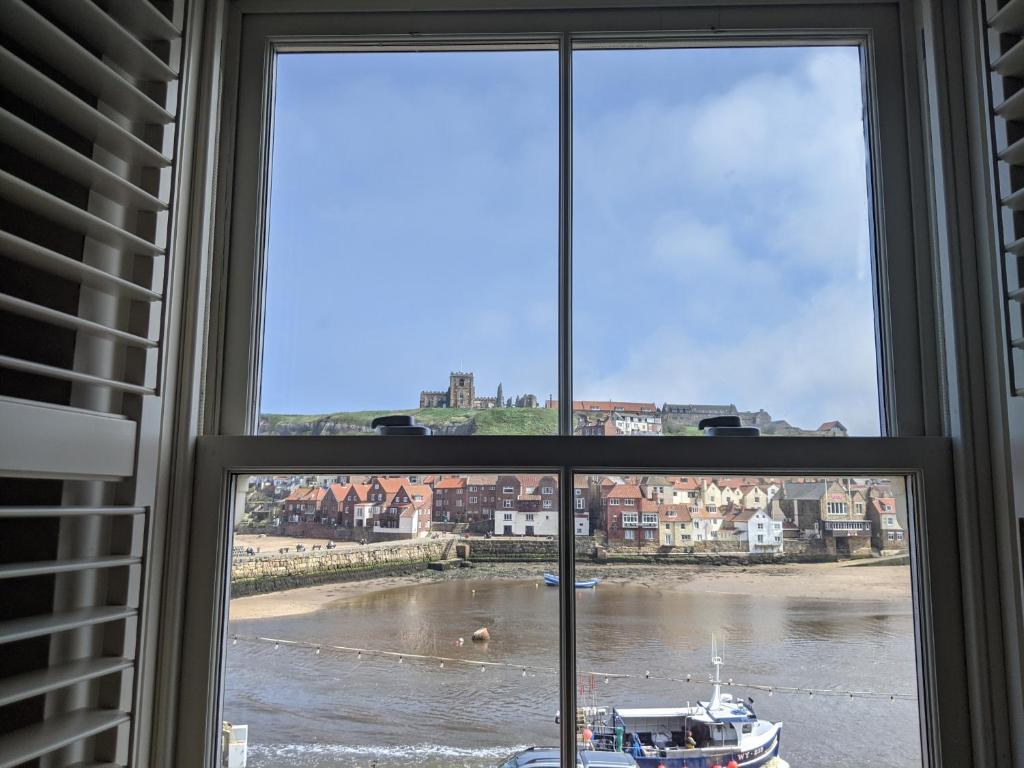 a window with a view of a boat in the water at Whitby Sea View Cottage in Whitby