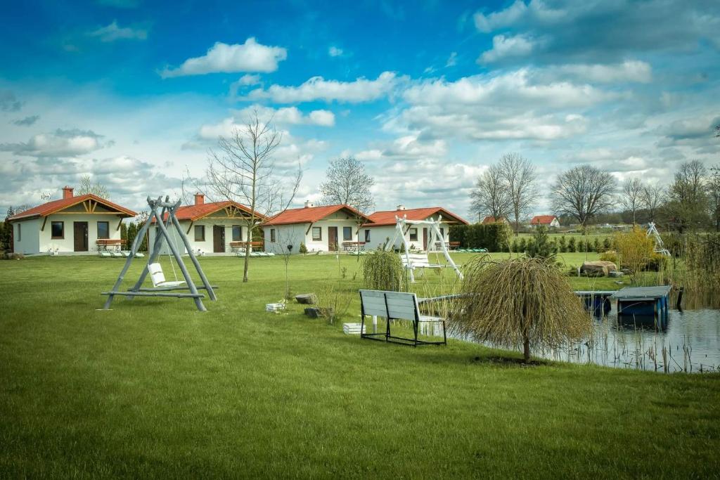 een park met een bank, een vijver en huizen bij Natalia Rest domki & camp in Tałty