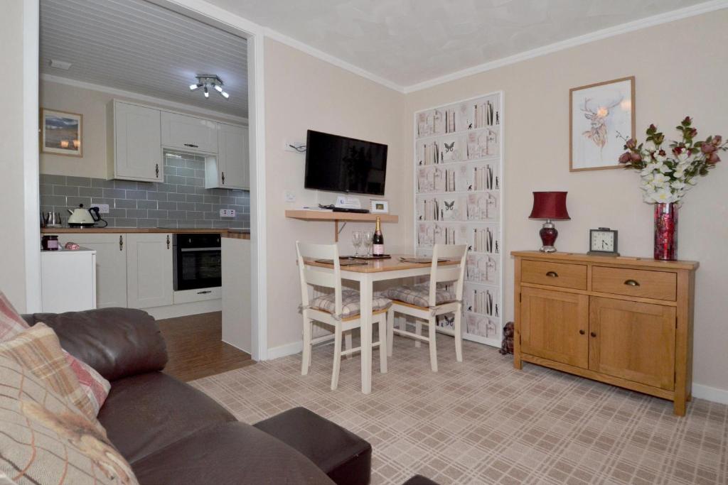 a living room with a kitchen and a table with chairs at The Bridge Suite in Invermoriston