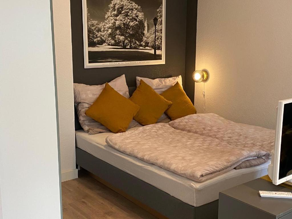 Bett mit gelben Kissen auf einem Zimmer in der Unterkunft Ferienwohnung am Stötteritzer Wäldchen in Leipzig