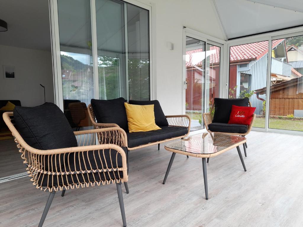 a living room with wicker chairs and a table at Ferienwohnung am Enzufer mit Wintergarten Bad Wildbad im Schwarzwald in Bad Wildbad