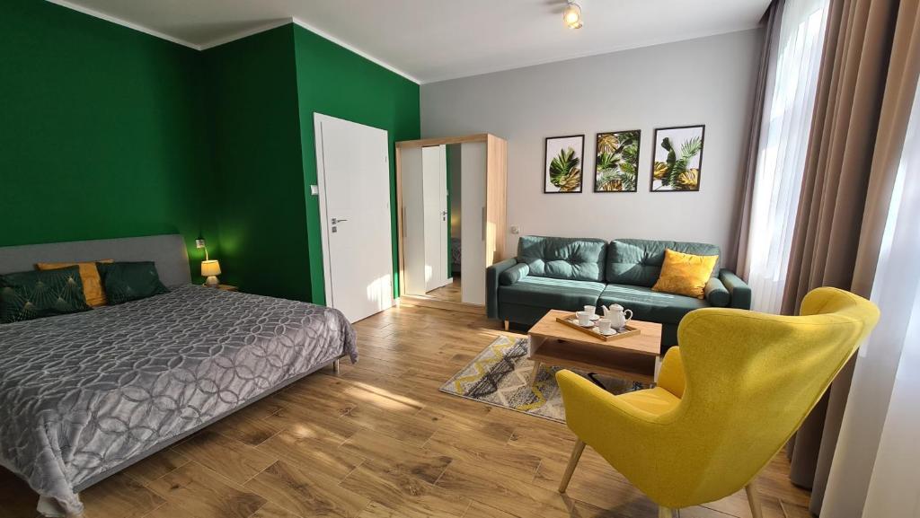 una camera da letto con pareti verdi, un letto e un divano di Apartament Parkowy Studio a Gniezno