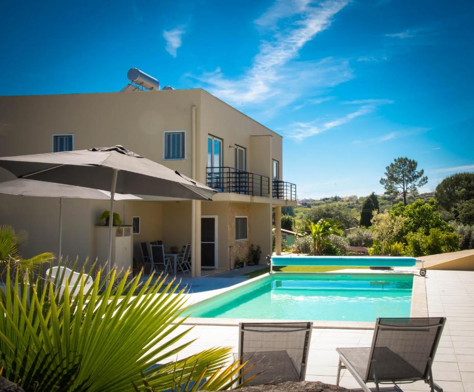 een villa met een zwembad en een parasol bij Casa Gemeos in Alcobaça