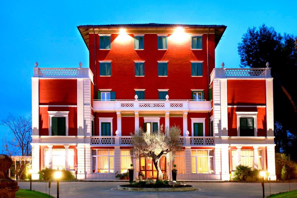 Un grand bâtiment rouge avec des lumières allumées dans l'établissement Hotel Villa Pigna, à Ascoli Piceno