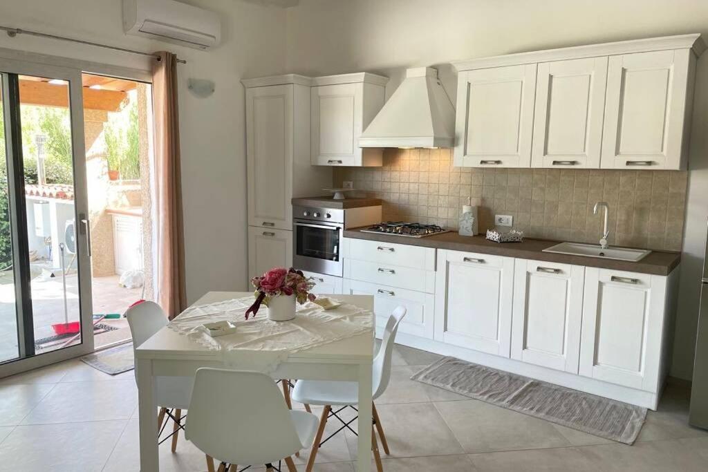 a kitchen with white cabinets and a table with chairs at Giorgia&Greta- relax casa vacanze in Olbia