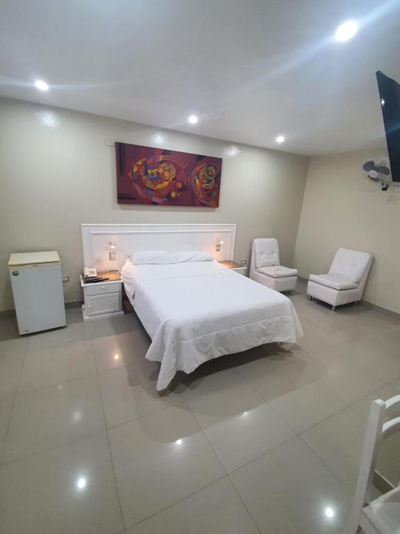sypialnia z białym łóżkiem i 2 krzesłami w obiekcie HOTEL CENTRAL w mieście Chiclayo