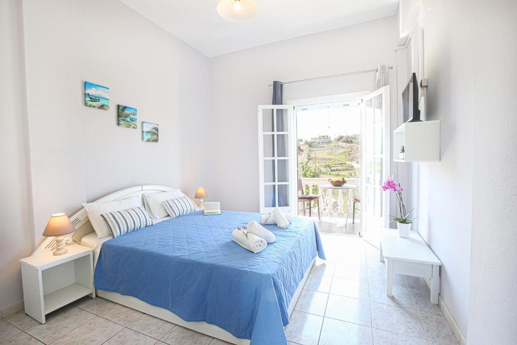 a white bedroom with a blue bed with two towels on it at Angela's house by the sea in Marathias