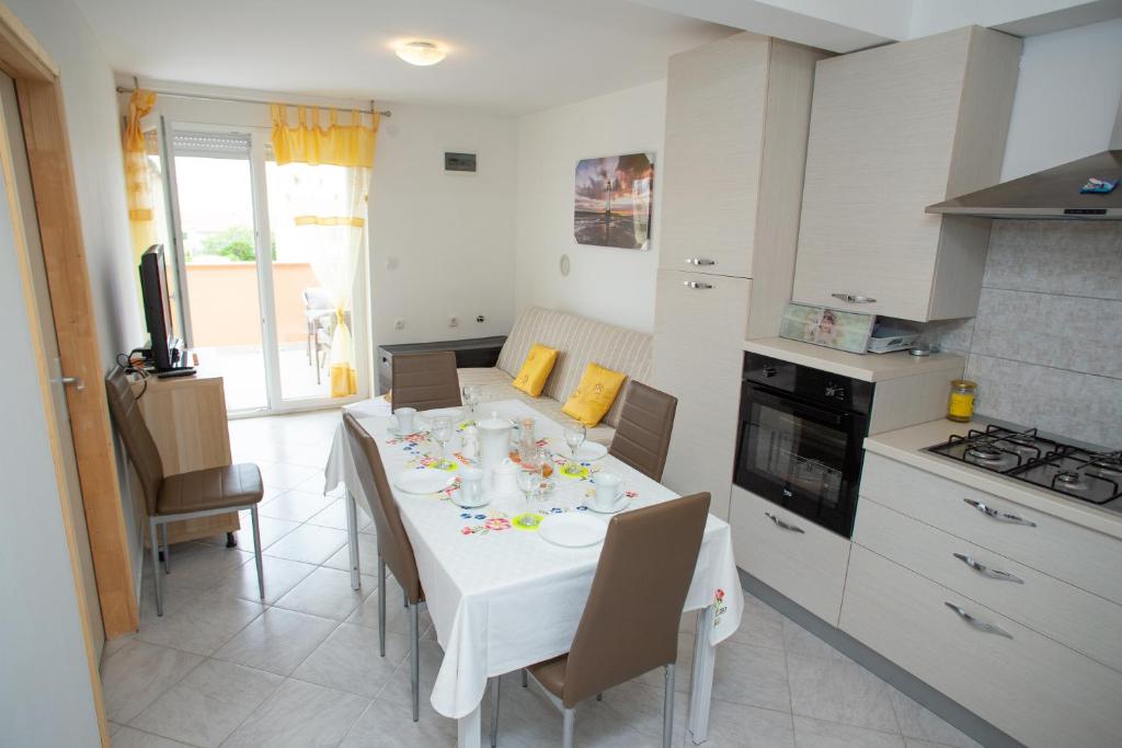 una cucina con tavolo e tovaglia bianca di Apartment Tara with pool a Povljana (Pogliana)