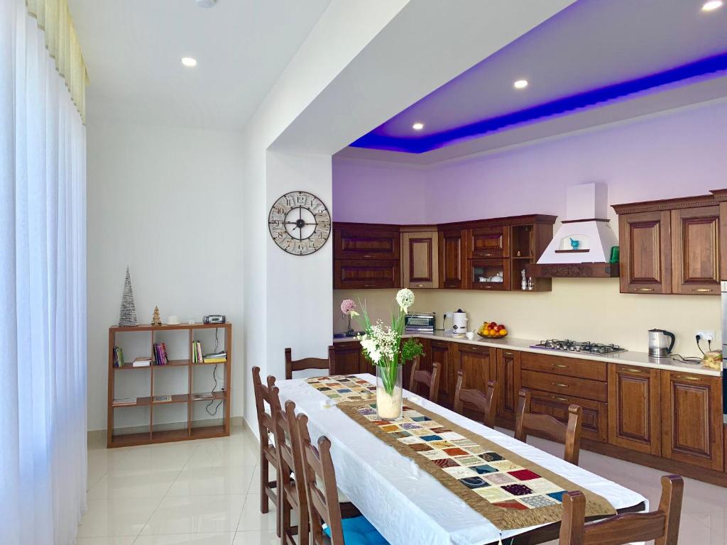 una cucina con tavolo lungo, sedie e bancone di Newly furnished appt in Gozo a Victoria