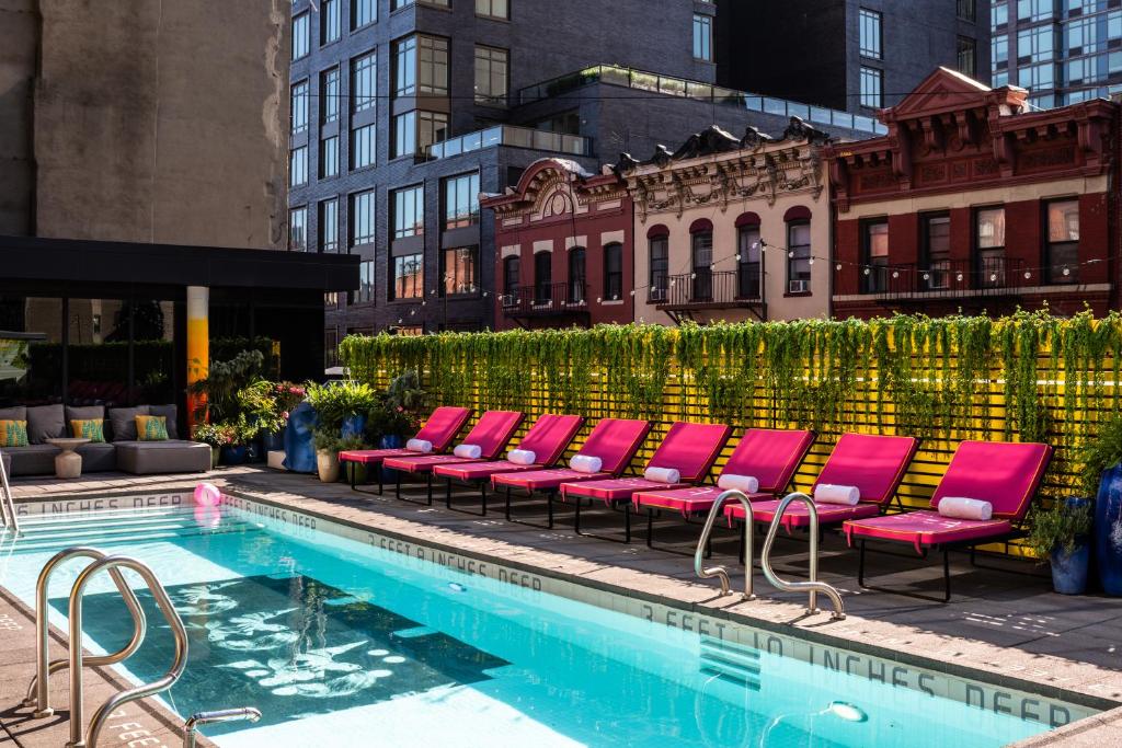 a row of pink chairs next to a swimming pool at Sixty LES in New York