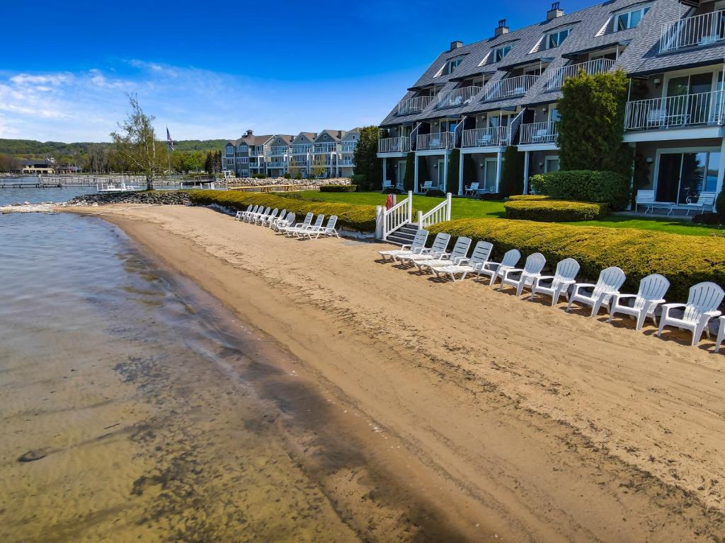 a beach with white chairs and a building at 109 Water Street Inn in Boyne City